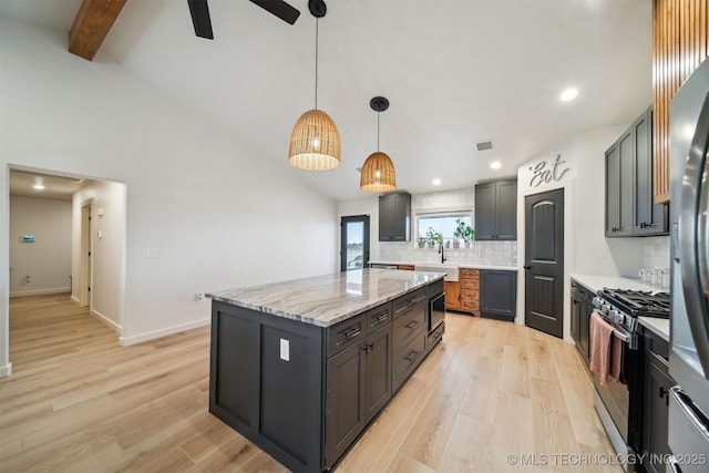 kitchen with stainless steel range with gas cooktop, decorative light fixtures, a center island, light stone countertops, and light hardwood / wood-style flooring