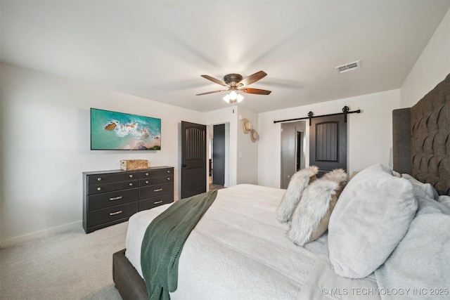 carpeted bedroom with ceiling fan and a barn door