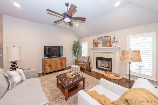 living room with hardwood / wood-style flooring, a tile fireplace, lofted ceiling, and ceiling fan