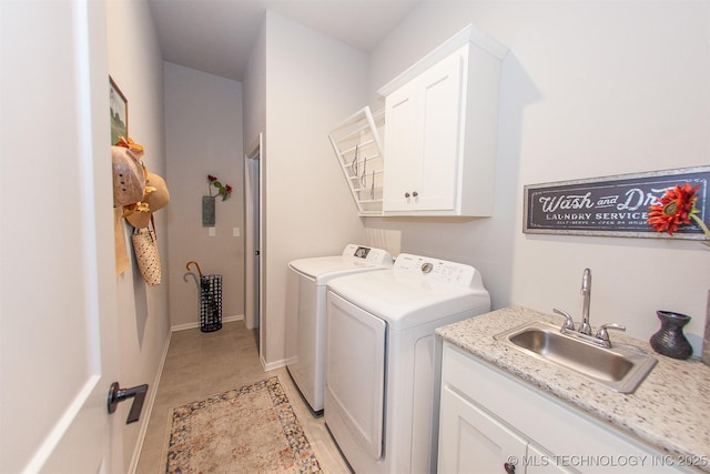 clothes washing area with sink, washing machine and dryer, and cabinets