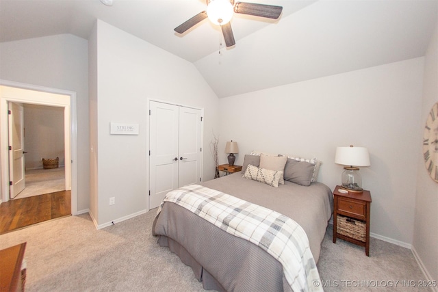 bedroom with ceiling fan, light colored carpet, vaulted ceiling, and a closet