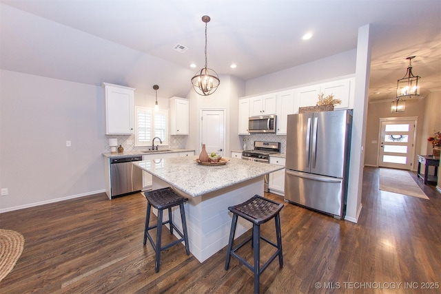 kitchen featuring sink, a center island, pendant lighting, stainless steel appliances, and white cabinets