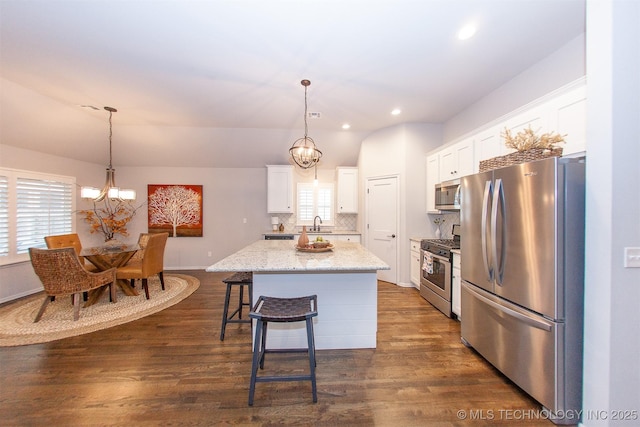 kitchen with decorative light fixtures, white cabinets, a chandelier, a center island, and stainless steel appliances