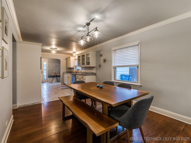 dining space with crown molding, sink, and hardwood / wood-style flooring