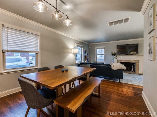 dining space with ornamental molding, dark hardwood / wood-style floors, and a premium fireplace