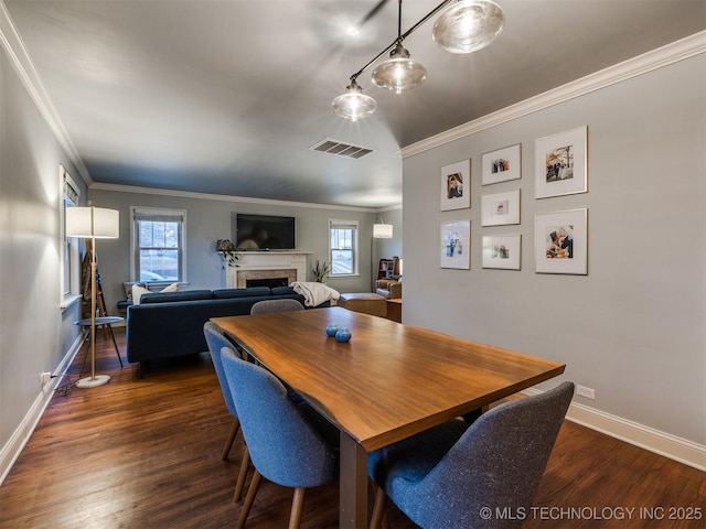 dining room with crown molding, dark wood-type flooring, and a wealth of natural light