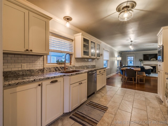 kitchen featuring appliances with stainless steel finishes, sink, backsplash, dark stone counters, and crown molding