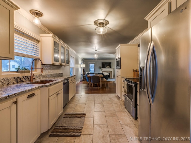 kitchen with sink, crown molding, tasteful backsplash, appliances with stainless steel finishes, and light stone countertops