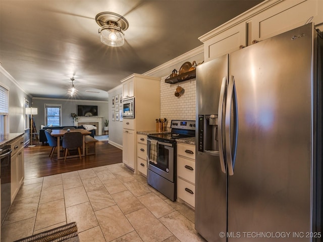 kitchen featuring tasteful backsplash, ornamental molding, appliances with stainless steel finishes, ceiling fan, and dark stone counters