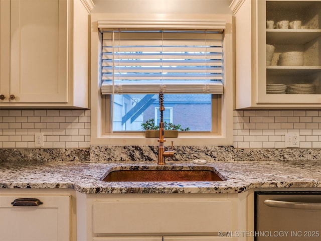 interior details with light stone counters, dishwasher, sink, and white cabinets