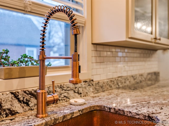 interior details featuring tasteful backsplash, sink, and light stone counters