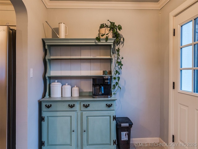 interior space with stainless steel fridge and ornamental molding