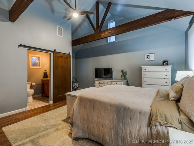 bedroom featuring beamed ceiling, ensuite bathroom, a barn door, and light wood-type flooring