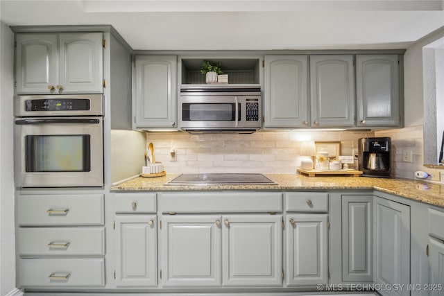 kitchen with stainless steel appliances, gray cabinets, and decorative backsplash