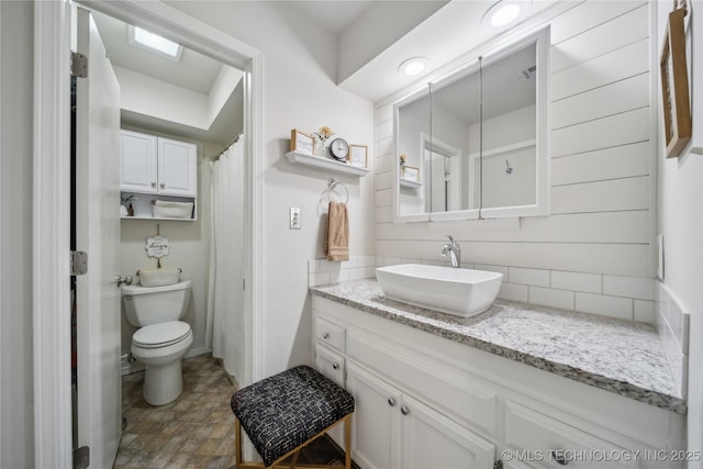 bathroom with vanity, decorative backsplash, and toilet