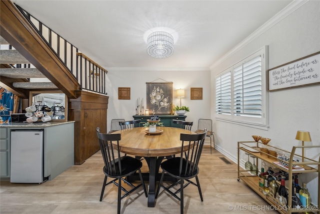 dining area featuring crown molding and light hardwood / wood-style flooring