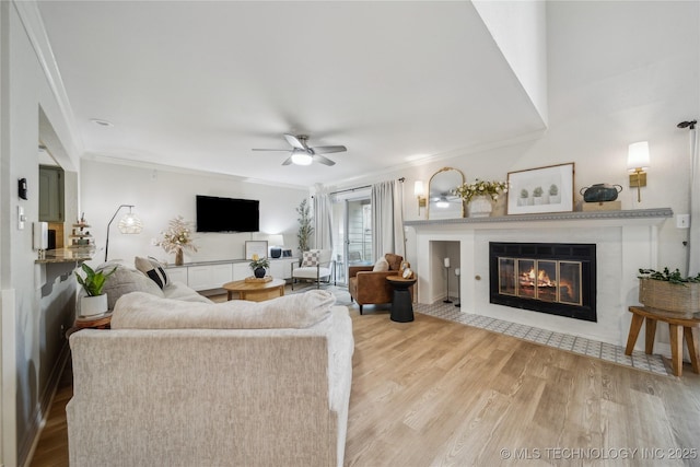 living room with crown molding, ceiling fan, and light wood-type flooring