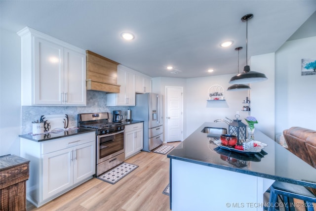 kitchen featuring tasteful backsplash, light hardwood / wood-style flooring, appliances with stainless steel finishes, pendant lighting, and white cabinets