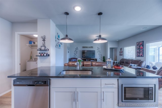 kitchen with white cabinetry, hanging light fixtures, dark stone counters, and appliances with stainless steel finishes