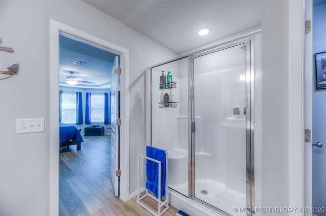 bathroom featuring hardwood / wood-style flooring, ceiling fan, and a shower with shower door