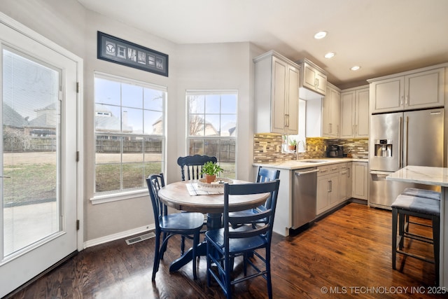 kitchen with tasteful backsplash, sink, dark wood-type flooring, and stainless steel appliances