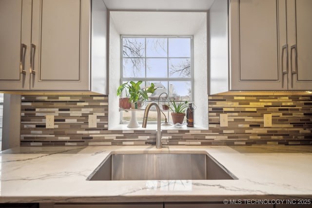 kitchen with tasteful backsplash, sink, gray cabinets, and light stone countertops