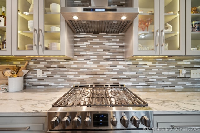 kitchen featuring light stone countertops, gray cabinetry, exhaust hood, and stainless steel range oven