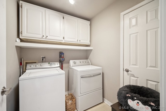 clothes washing area with cabinets and washing machine and clothes dryer