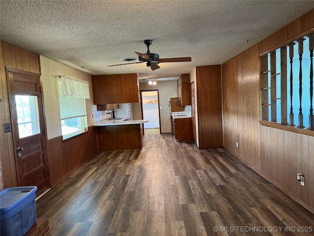 kitchen featuring ceiling fan, wooden walls, dark hardwood / wood-style floors, and kitchen peninsula