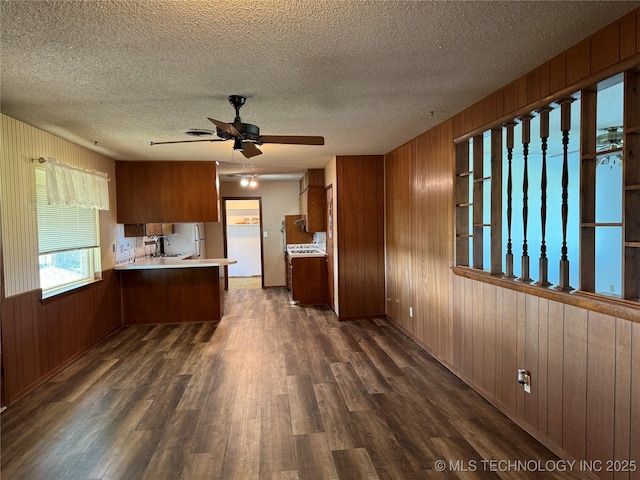 kitchen with sink, ceiling fan, wooden walls, dark hardwood / wood-style floors, and kitchen peninsula