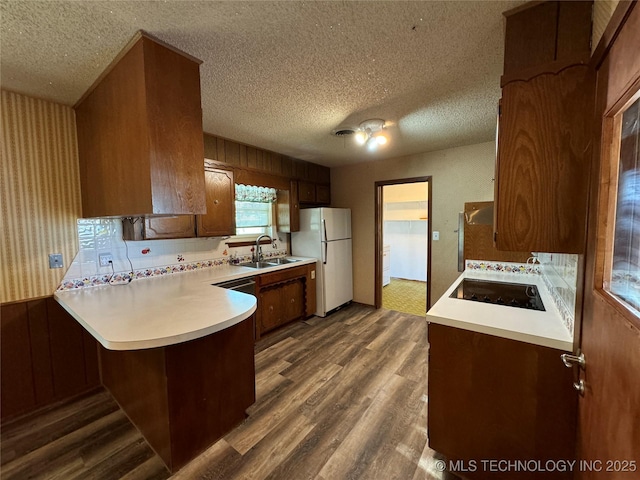 kitchen featuring sink, a textured ceiling, dark hardwood / wood-style flooring, kitchen peninsula, and white fridge