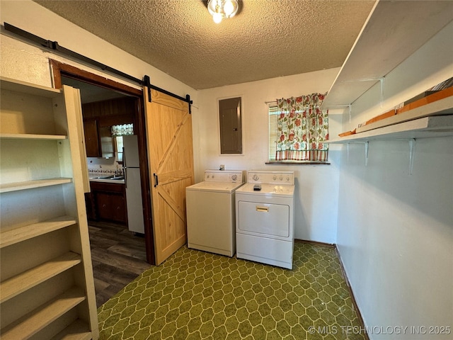 laundry room with separate washer and dryer, sink, electric panel, a barn door, and a textured ceiling