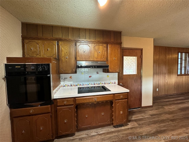 kitchen with vaulted ceiling, tasteful backsplash, dark hardwood / wood-style flooring, black appliances, and a textured ceiling