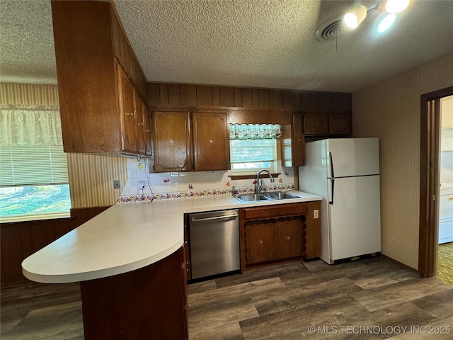 kitchen with sink, dishwasher, dark hardwood / wood-style floors, white refrigerator, and kitchen peninsula