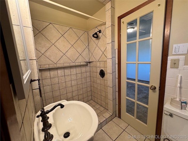 bathroom featuring a tile shower, sink, tile patterned floors, and toilet