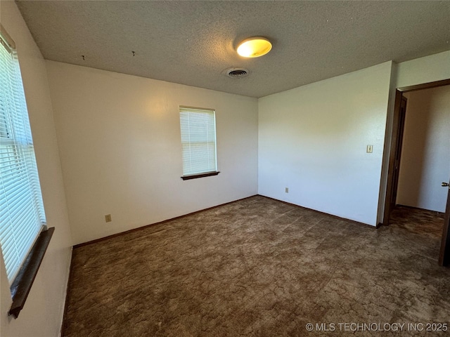 spare room with dark carpet and a textured ceiling