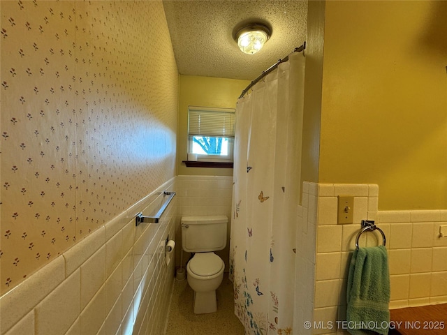 bathroom with tile walls, toilet, and a textured ceiling