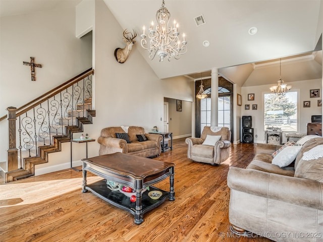 living room with hardwood / wood-style flooring, high vaulted ceiling, a chandelier, and ornate columns