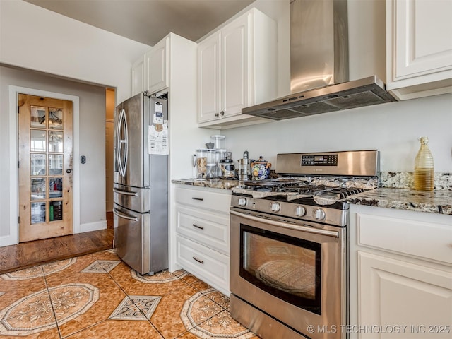 kitchen with light tile patterned floors, appliances with stainless steel finishes, light stone counters, white cabinets, and wall chimney exhaust hood