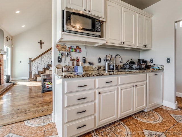 kitchen with lofted ceiling, sink, white cabinets, light tile patterned flooring, and dark stone counters