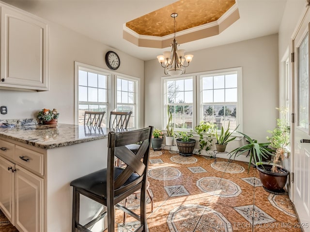 interior space featuring a raised ceiling, white cabinetry, and light stone countertops