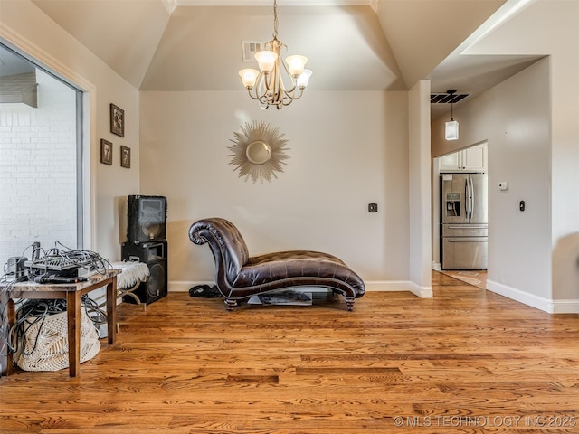 sitting room with lofted ceiling, an inviting chandelier, and light hardwood / wood-style floors