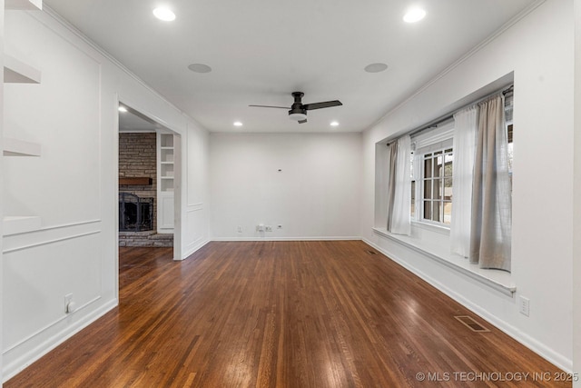 unfurnished living room with ceiling fan, a stone fireplace, dark hardwood / wood-style flooring, and built in shelves