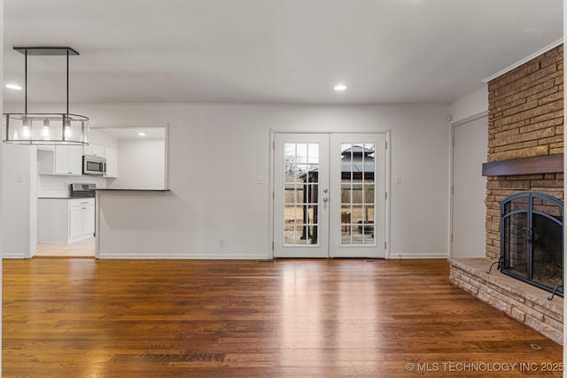 unfurnished living room with a brick fireplace, dark wood-type flooring, and french doors