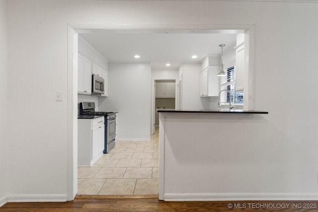 kitchen featuring white cabinetry, appliances with stainless steel finishes, kitchen peninsula, and decorative light fixtures