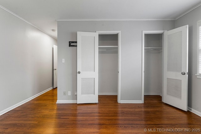 unfurnished bedroom with crown molding, two closets, and dark hardwood / wood-style flooring