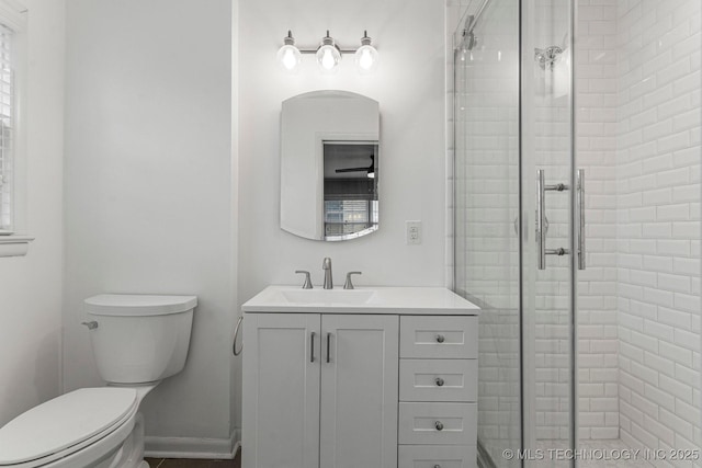 bathroom with a shower with door, vanity, and toilet