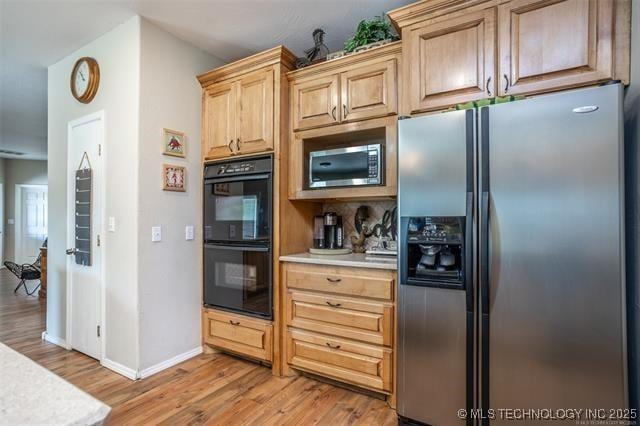 kitchen with appliances with stainless steel finishes, light brown cabinets, and light hardwood / wood-style flooring