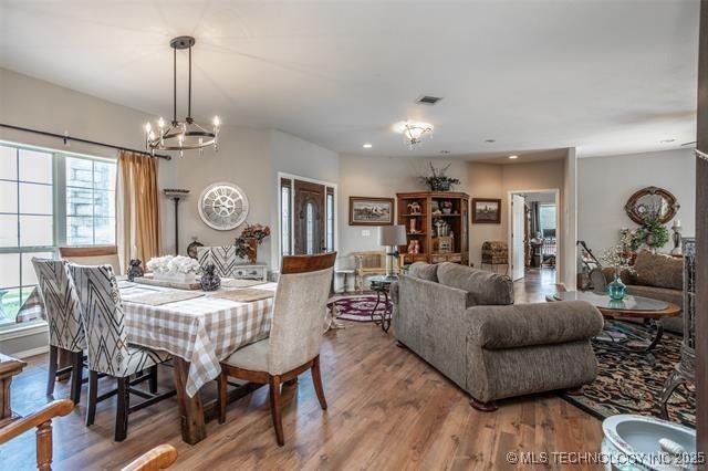 dining area with a healthy amount of sunlight, hardwood / wood-style floors, and a notable chandelier