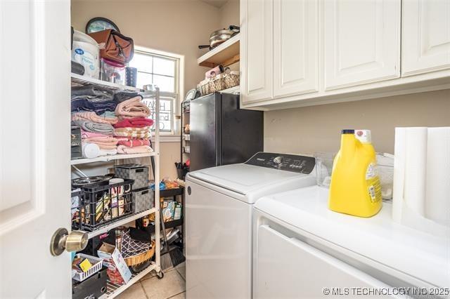 laundry area with separate washer and dryer, light tile patterned floors, and cabinets